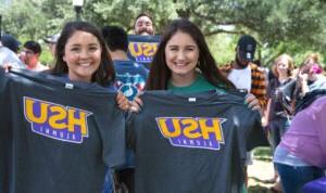 HSU graduates holding up tee shirts that read "HSU Alumni"